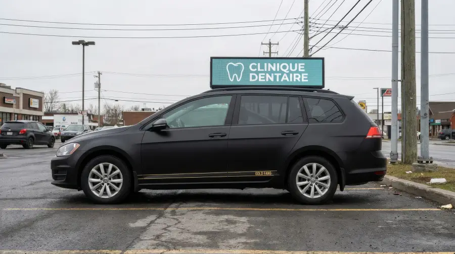 L’auto dans un stationnement commercial, l’écran affichant l’annonce d’une clinique dentaire